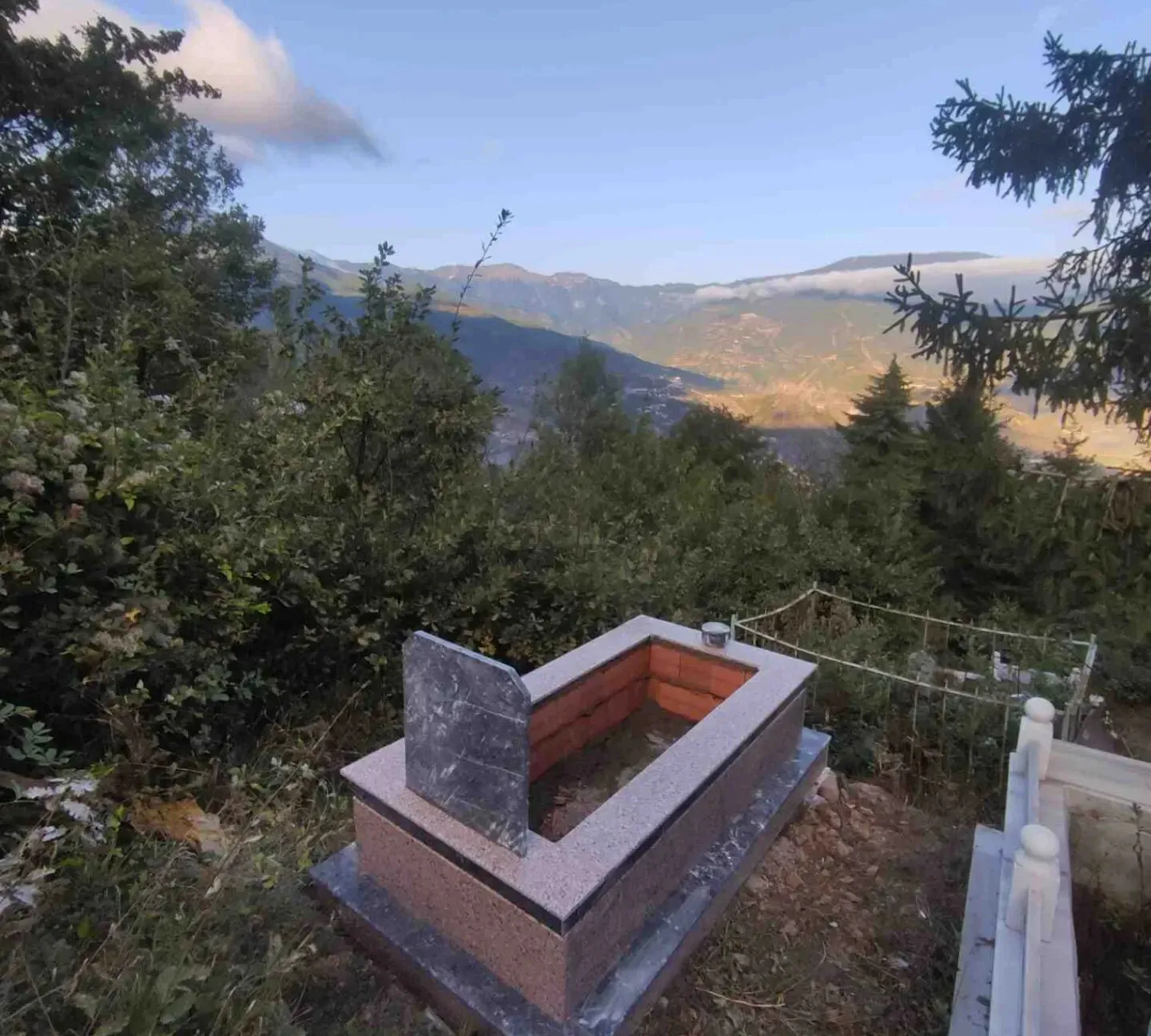 Açık renk granit mezar, dağ manzaralı mezarlıkta